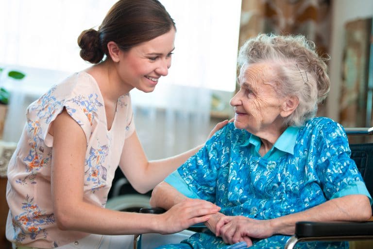 Elderly woman on wheelchair with a home health care CNA